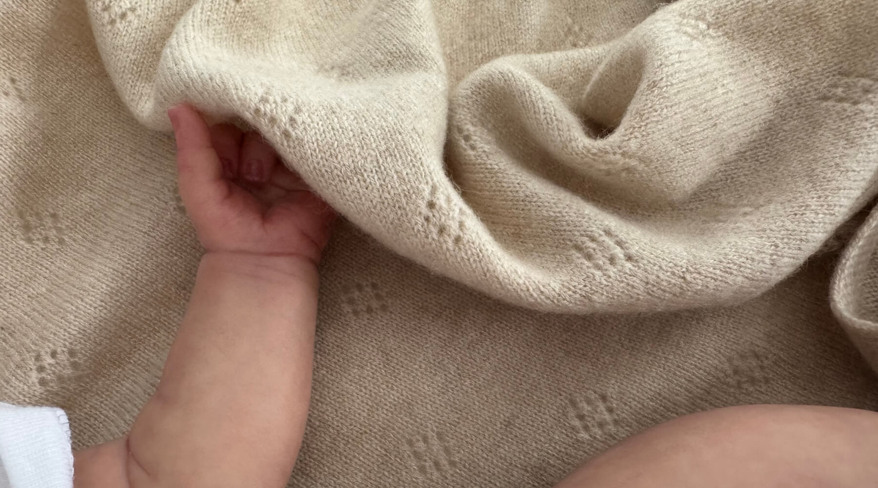 Baby touching a cashmere baby blanket